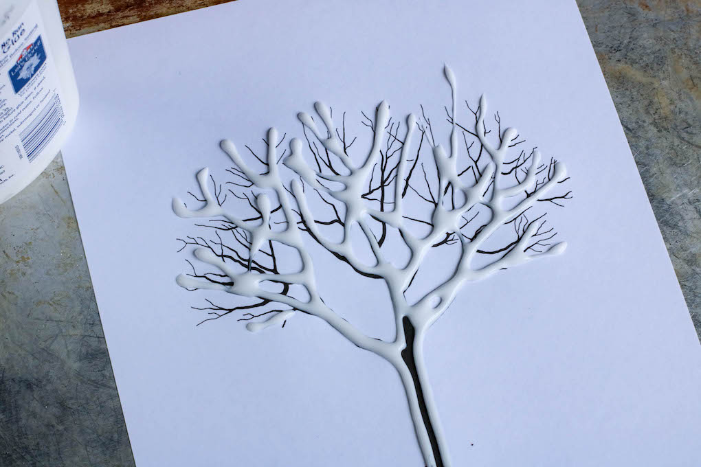 Adding glue to the tree to make a salt painting easy painting ideas for kids
