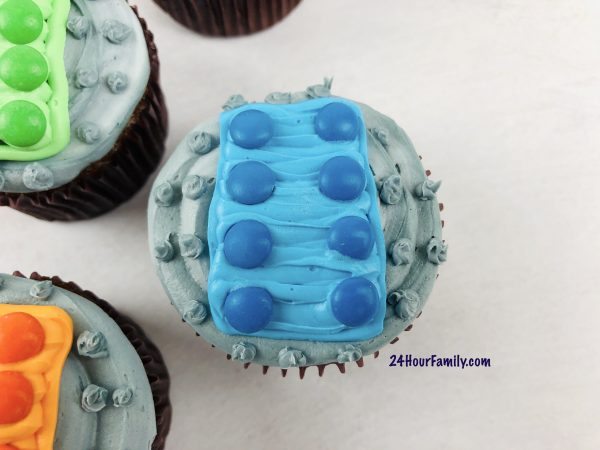 Blue lego cupcakes that are easy to make from a cake mix with adding a rectangle to the top of the cupcake and then adding blue M&M's to make the lego cupcake resemble a lego brick