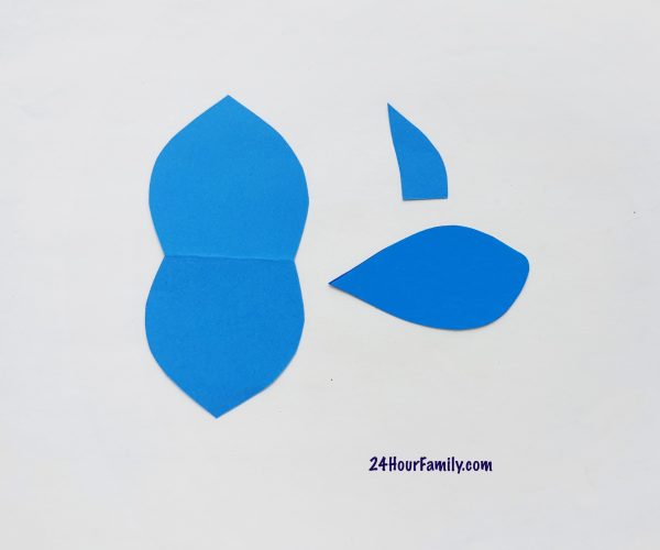 Blue craft papers cut out using a fish template that includes the body of the fish, tail and fins