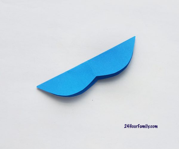 Take the tail-fin paper cutout made from  a fish template and fold it into half length-wise. 