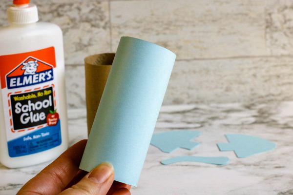 Cut another sheet of paper to fit the cardboard tube, approximately 4 inches by 6 inches. Glue the paper to the cardboard tube.