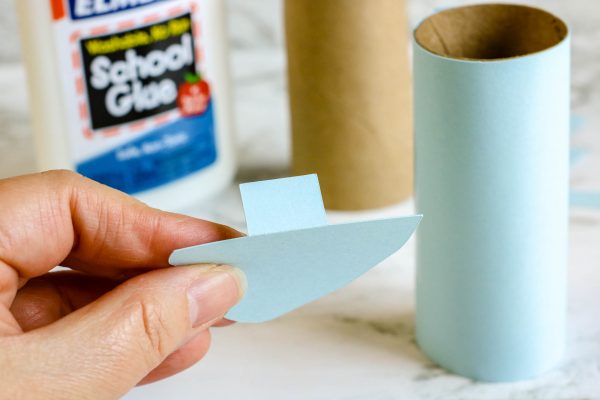 To make the easy toilet paper roll elephant craft - take remaining scrap paper, approximately 1 inch by 2 inches. Glue these tabs to the flat edge of the elephant ears. Allow to dry.