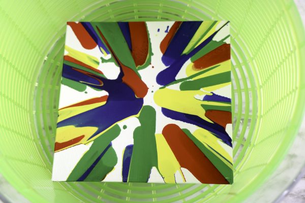 Colorful paint splash on paper inside a green salad spinner