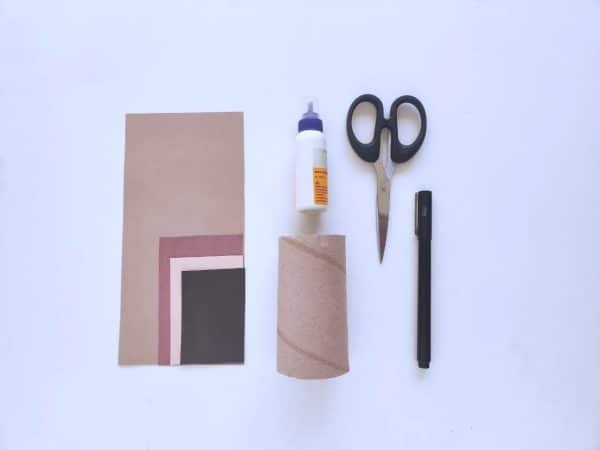 Craft supplies: colored papers, glue, scissors, pen, and roll on white background
