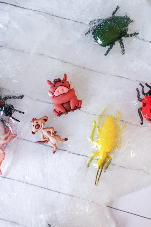 Toy bugs and animal figurines on a textured white surface resembling bug slime