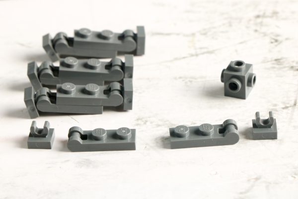 Disassembled grey LEGO pieces on a white background