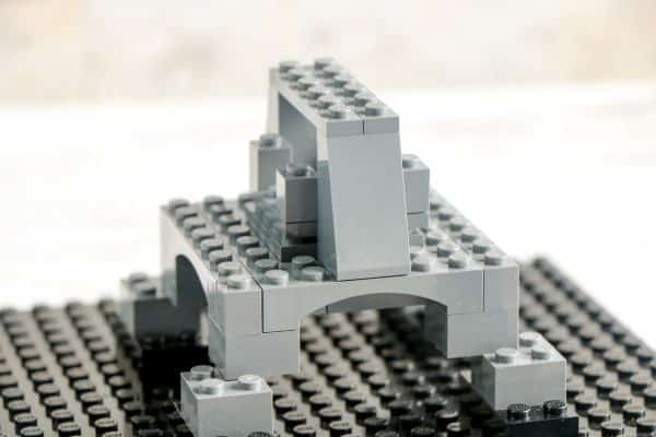 LEGO structure with an arch and pillars, constructed on a black baseplate