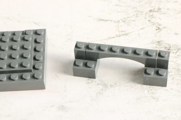 A grey LEGO arch and a 6x6 plate on a marble surface