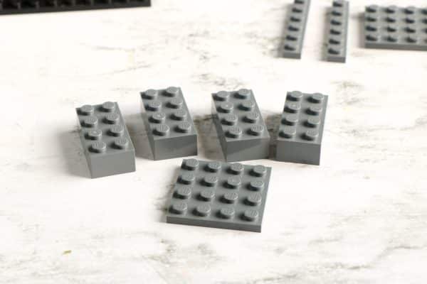 Multiple grey LEGO bricks scattered with a black baseplate in the background