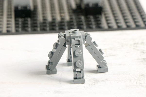 LEGO structure resembling a tripod or robot legs with a central hinge, built from grey LEGO pieces