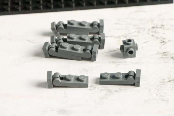 Various grey LEGO bricks scattered on a white surface
