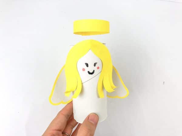 Yellow angel hair cutout beside colorful scissors, Angel cutout template with white glue and colorful scissors, How to Make an Angel Toilet paper Craft with Free Angel template, DIY Angel Toilet Paper Craft with yellow halo and wings, Angel Craft, Angel Toilet paper Roll, Angel' Wings, Crafts For Kids, Craft supplies for angel DIY: paper roll, scissors, markers, and glue, Cut-out angel craft pieces and colorful scissors, Toilet paper roll angel with yellow hair and pink and black markers, Hand holding a toiler paper roll angel with yellow hair, a smiling face, and a yellow halo