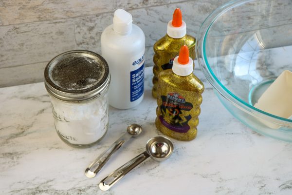 ingredients needed to make St. patrick's day slime, gold glitter glue glue, contact lens solution