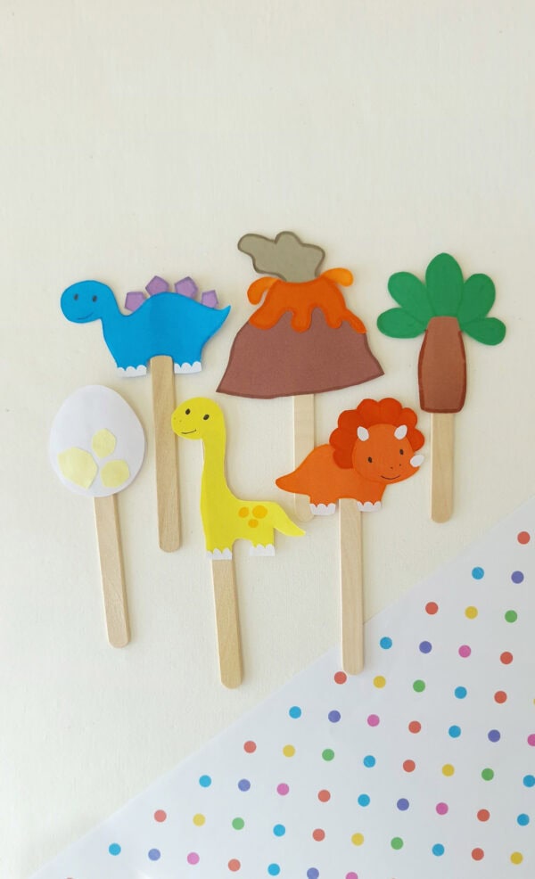 Colorful dinosaur-themed popsicle stick puppets including volcano, tree, and egg designs.