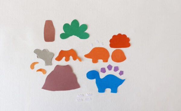 Cut-out shapes for assembling dinosaur-themed popsicle stick puppets, including dinosaurs, a volcano, tree, and other elements.