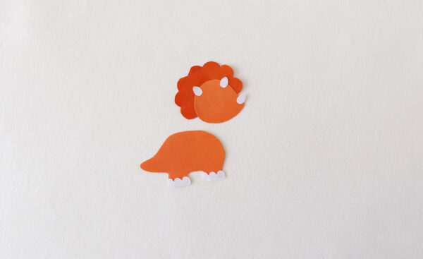 Partially assembled orange dinosaur with added horns and feet for a popsicle stick puppet.