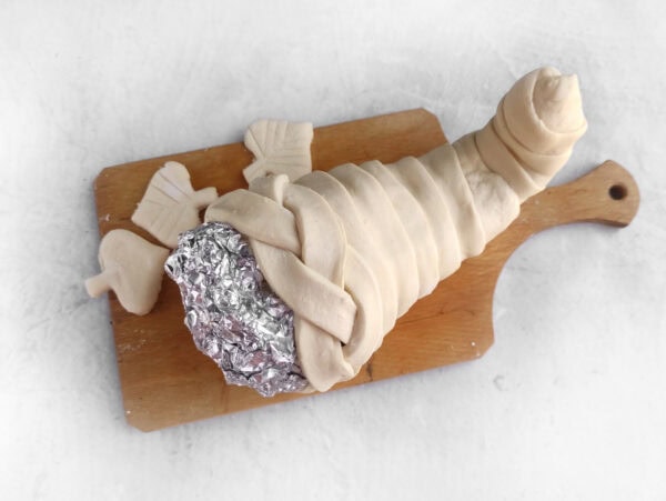Puff pastry wrapped around a foil cornucopia mold before baking.