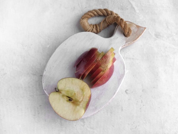 Thinly sliced apple on a decorative cutting board.