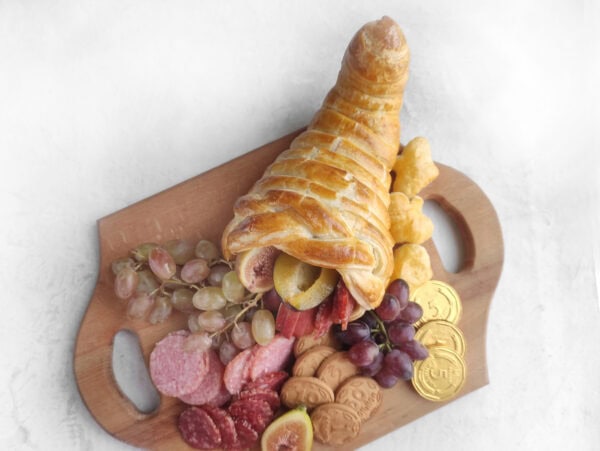 Baked puff pastry cornucopia on a small charcuterie board.