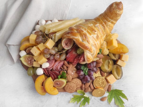Thanksgiving cornucopia charcuterie board with puff pastry horn and seasonal snacks.