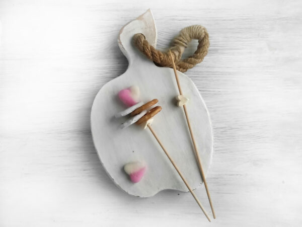 For the fancy flower, gather pretzels, marshmallows, and marmalade hearts. First, skewer a marshmallow as a stopper for the arrangement. Then, alternate threading regular and chocolate pretzels. Feel free to add as many pretzels as you like. Finish by adding a marmalade heart on top. You now have four fancy flowers.
