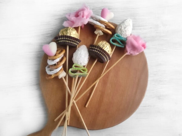 Assemble the bouquet on the board by arranging your handcrafted flowers and adding FERRERO ROCHER chocolates on skewers. Alternate the sweets so the board looks balanced. Trim any skewers that extend beyond the board’s handle. Finally, wrap the bouquet in paper and tie it with a ribbon.