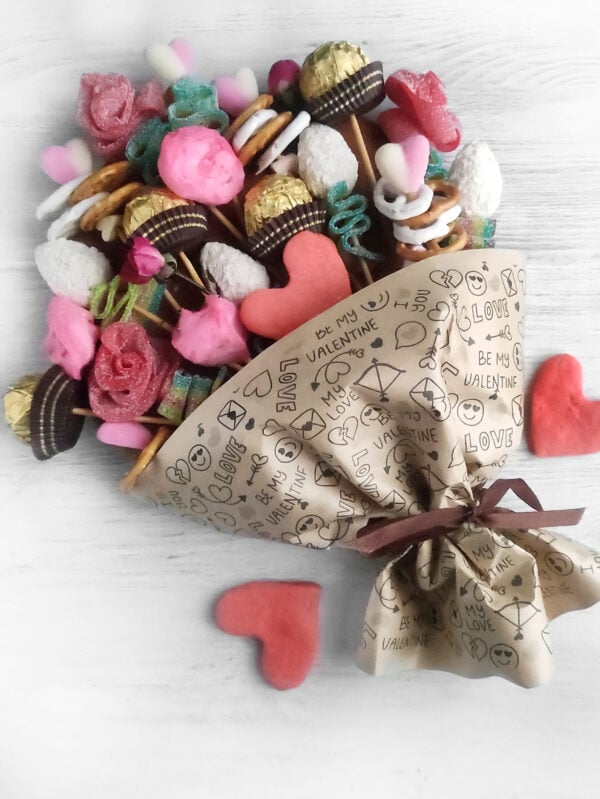 A stunning candy bouquet charcuterie board for Valentine’s Day, filled with an assortment of sweet treats like truffles, candy hearts, and chocolate bars, creating a delightful and decorative centerpiece.