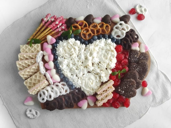 A beautifully arranged Valentine’s dessert board with pretzels, wafers chocolates, and candy hearts for a sweet celebration.