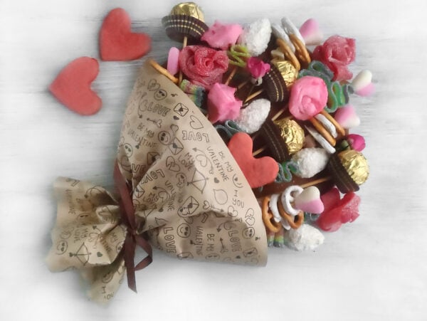 A festive Valentine's Day candy bouquet charcuterie board, overflowing with a mix of chocolates, heart-shaped gummies, and colorful confections for a sweet celebration.