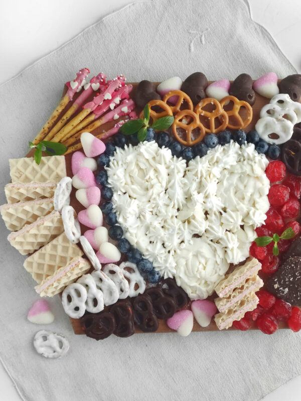 A vibrant Valentine's dessert charcuterie board filled with chocolates, cookies, and heart-shaped treats for a festive celebration.