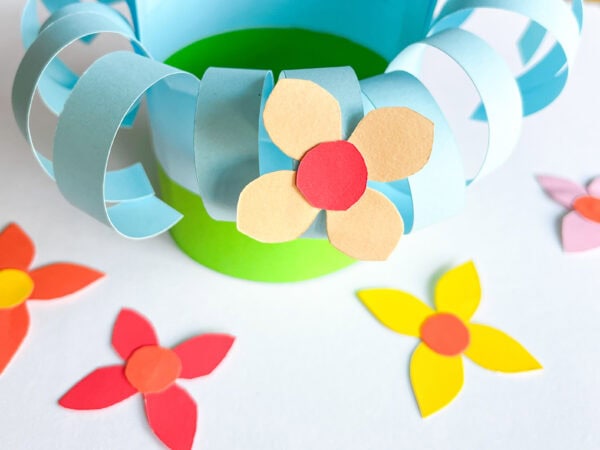 Partially decorated basket with multiple colorful flowers attached to the curled blue strips