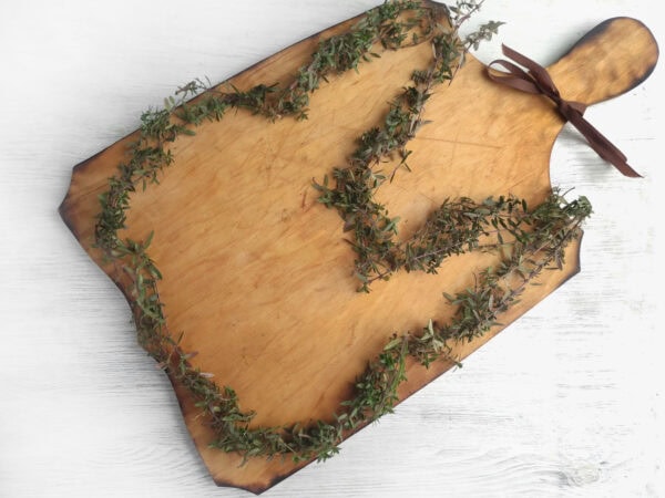 A rustic wooden board decorated with fresh thyme in the shape of a bunny.