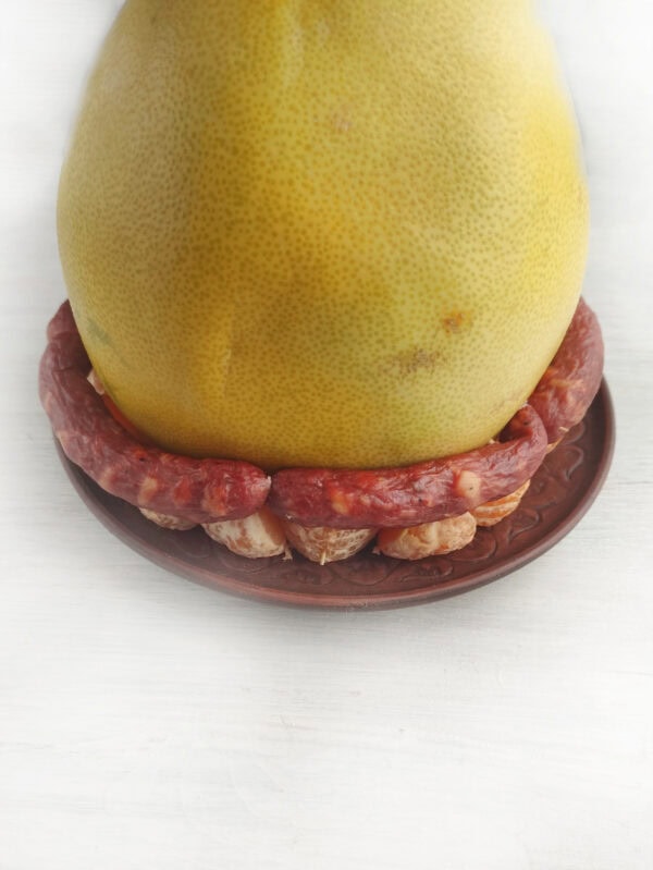 Pomelo sitting on a base of tangerine segments, surrounded by a ring of sausages