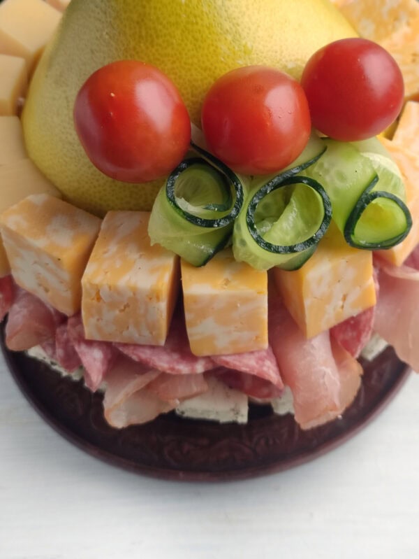 Cherry tomatoes and cucumber spirals over a layer of marbled cheese cubes and rolled meats.