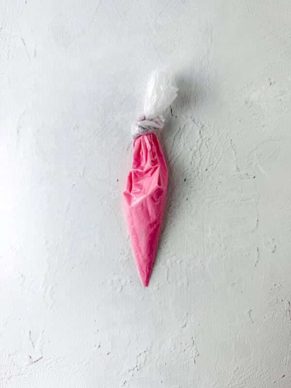 Piping bag filled with melted pink candy melts for decorating