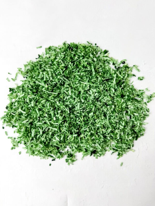 Green-dyed shredded coconut spread out on a white surface