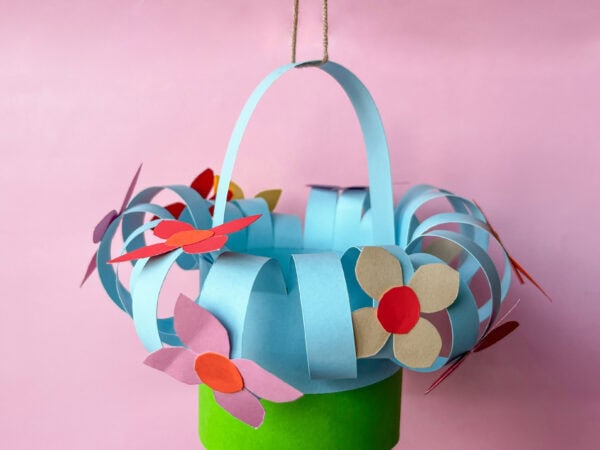 Hanging flower basket with a green base, blue curled strips, and colorful flower decorations