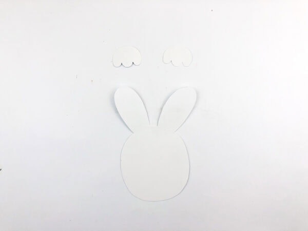 A white bunny face and paws cut out from paper.
