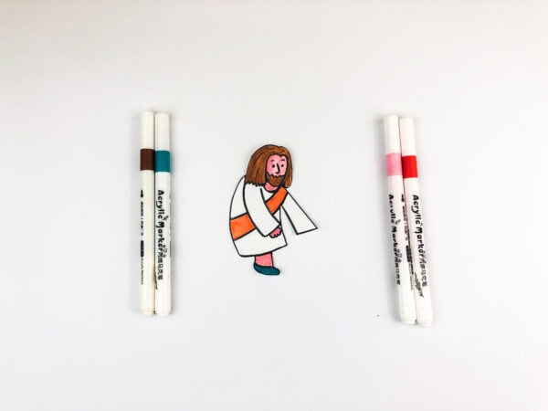 A cutout of Jesus with coloring markers around it.