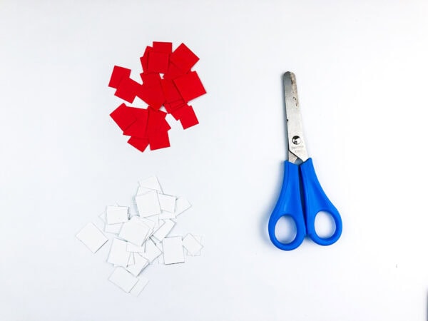 Cut red and white paper squares with scissors