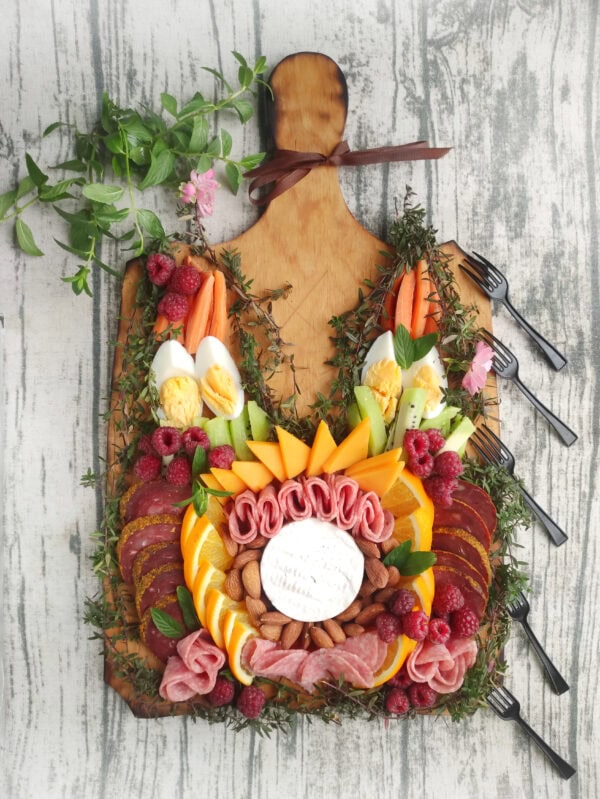 A fully arranged charcuterie board and small black forks placed around it.