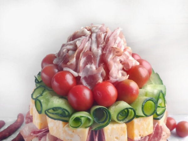 Pomelo topped with bacon, surrounded by cherry tomatoes and cucumber spirals