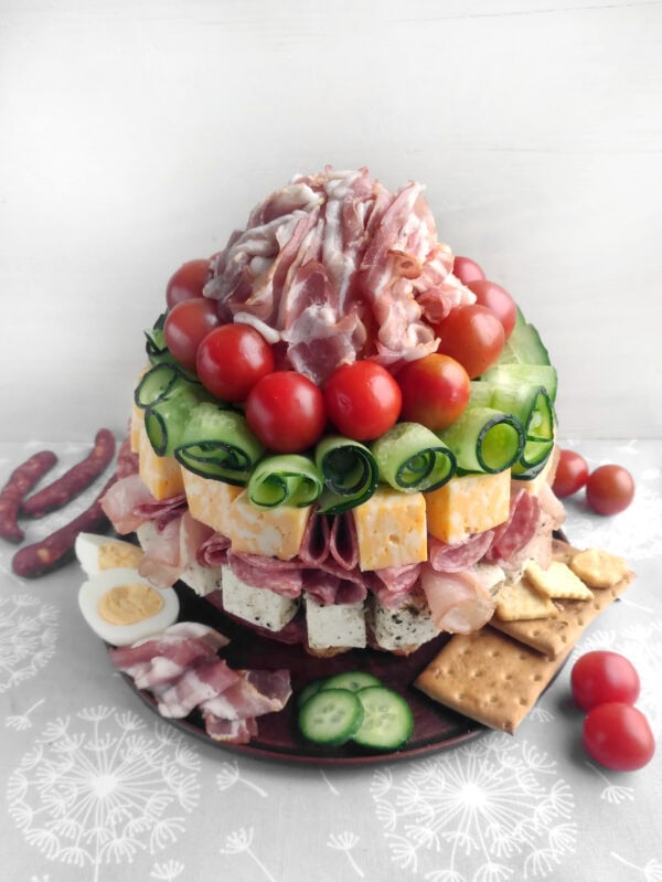 Charcuterie tower with layers of meats, cheeses, and vegetables