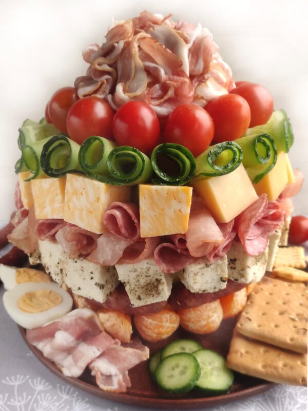 Full multi-layer charcuterie tower with various toppings like meat, cheese, vegetables, and fruits