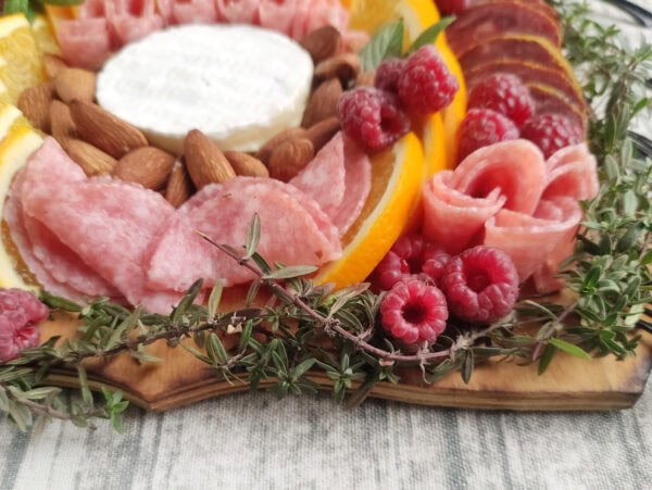 Another close-up of the charcuterie board focusing on folded salami slices, and raspberries