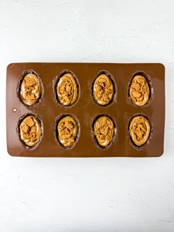 Chocolate egg molds filled with cookie butter and topped with crushed Biscoff cookies.