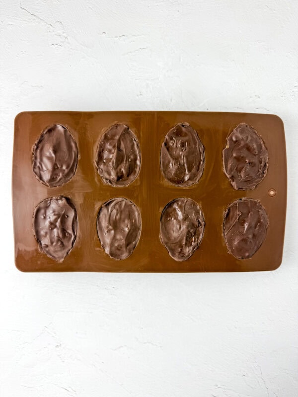 Chocolate eggs fully sealed with an additional layer of melted chocolate, ready to set before unmolding.