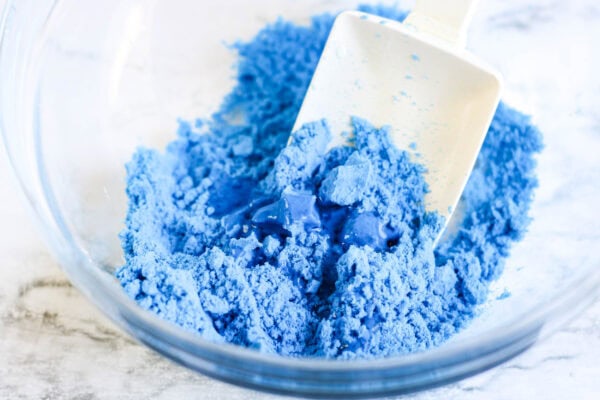 The blue sand starting to clump together as it's being mixed.