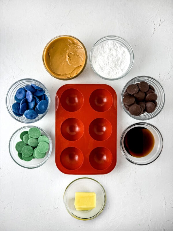 Ingredients and tools for making chocolate Earth balls arranged around a red silicone mold.