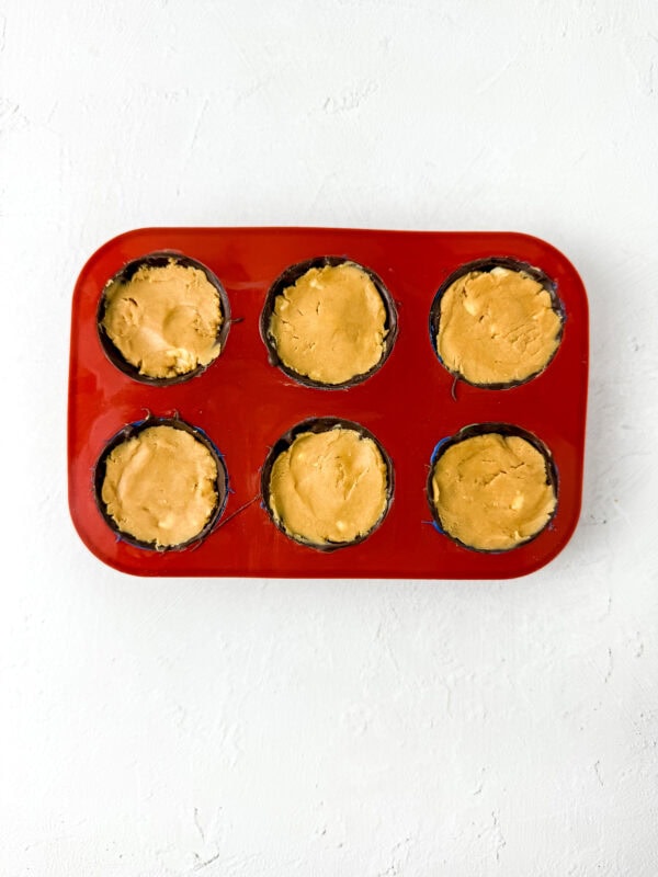 Mold filled with peanut butter mixture pressed into chocolate shells.